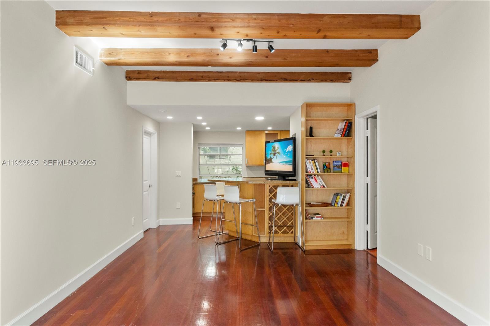 A room features hardwood floors, exposed wood ceiling beams, a bookshelf, and a kitchen bar — 1605 Euclid Ave # A1, Miami Beach FL 33139, MIAMI BEACH, FL