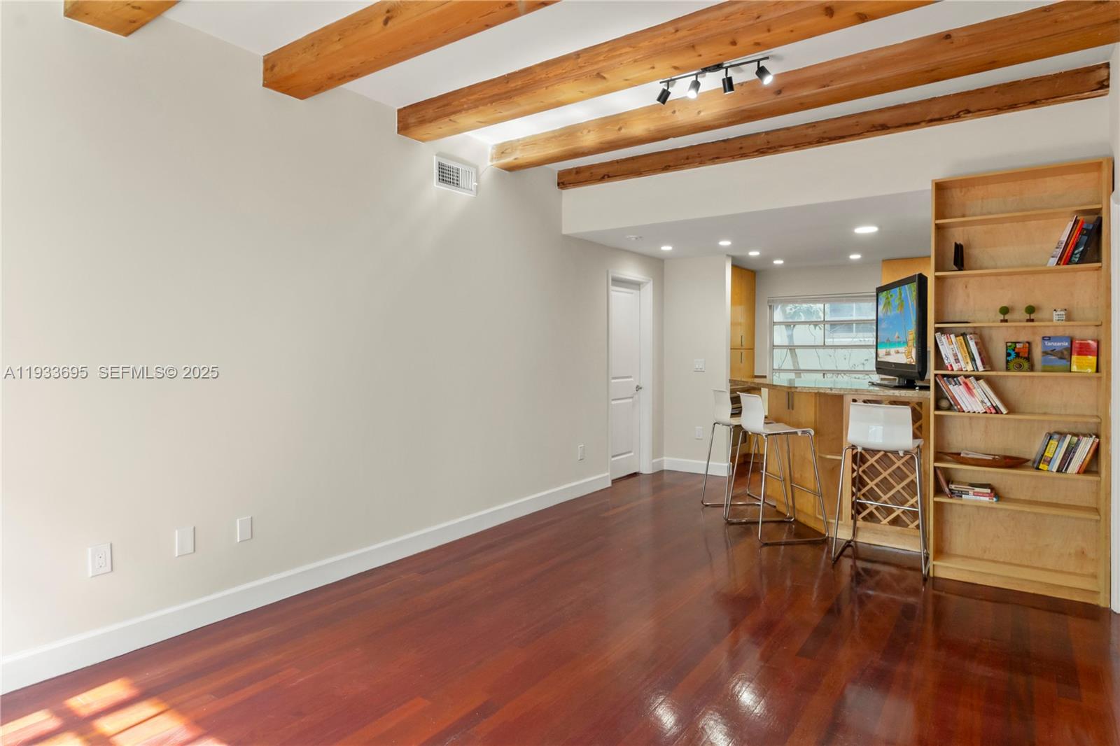 A living area with wood floors and exposed ceiling beams leads to a kitchen bar — 1605 Euclid Ave # A1, Miami Beach FL 33139, MIAMI BEACH, FL