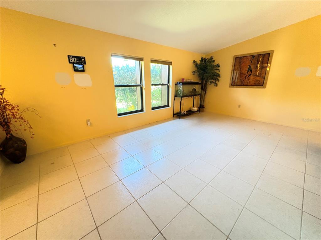 A living room with yellow walls, tile flooring, two windows, and a fish tank — 12 WESTGABLE PLACE, PALM COAST, FL