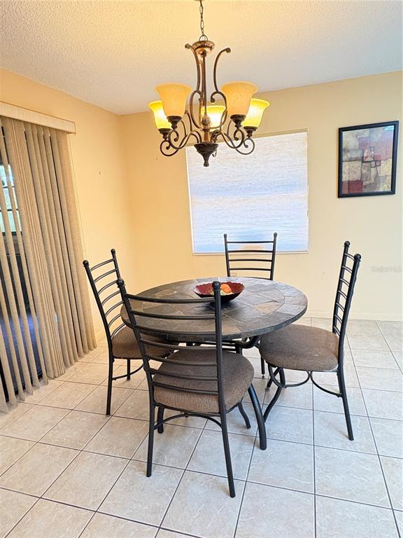 A dining area features a round slate-topped table, four metal chairs, and a chandelier — 12 WESTGABLE PLACE, PALM COAST, FL