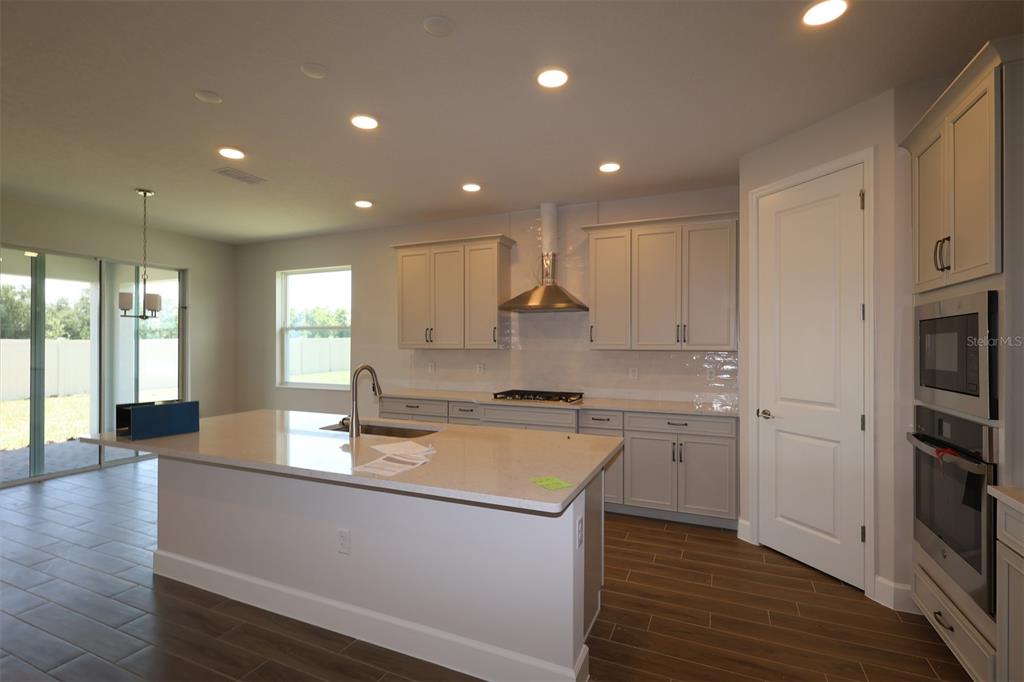 A light-colored house with vertical siding, a stone base, and a paver driveway — 3795 WOLVES CREEK PLACE, APOPKA, FL