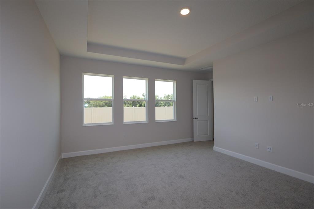 A modern kitchen features light-colored cabinetry, a large center island, and wood-look tile flooring — 3795 WOLVES CREEK PLACE, APOPKA, FL