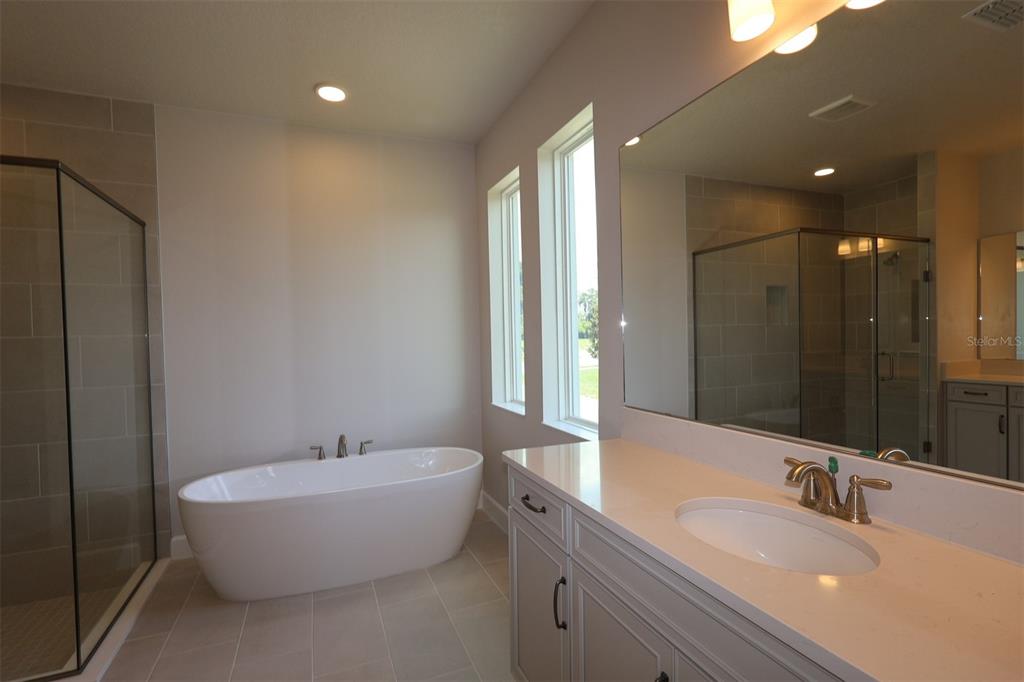 A modern kitchen features light gray cabinets, a large quartz island, and stainless steel appliances — 3795 WOLVES CREEK PLACE, APOPKA, FL