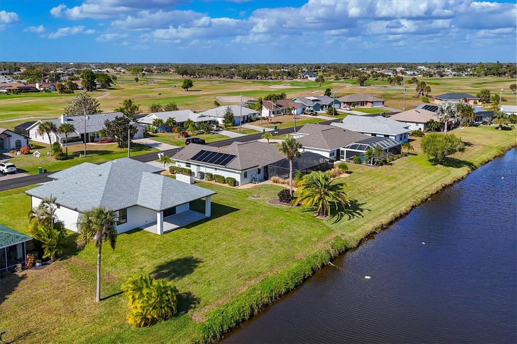 An aerial view shows several suburban houses with pools along a canal and golf course — 9 BUNKER PLACE, ROTONDA WEST, FL