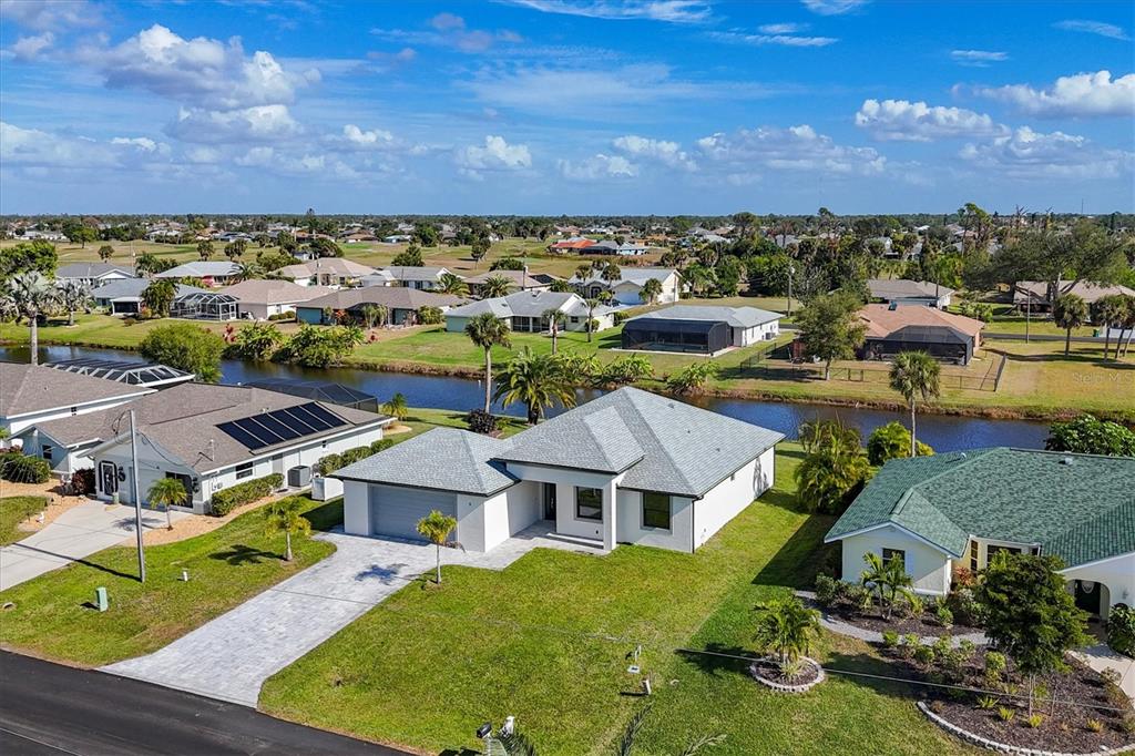 An aerial view shows a single-story house with a gray roof and a paved driveway — 9 BUNKER PLACE, ROTONDA WEST, FL