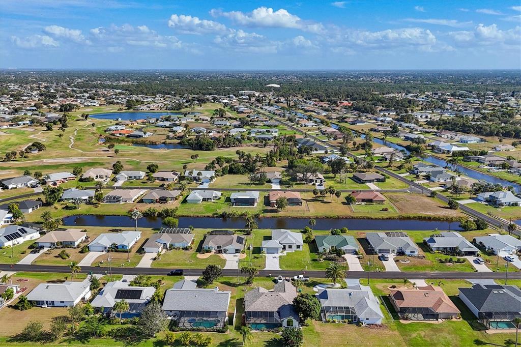 Aerial view of a suburban neighborhood featuring houses, a canal, and a golf course — 9 BUNKER PLACE, ROTONDA WEST, FL