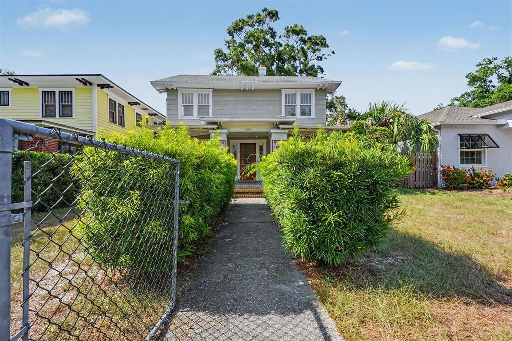 A two-story house with a gray exterior and a walkway flanked by tall green bushes — 5441 1ST AVENUE N, ST PETERSBURG, FL