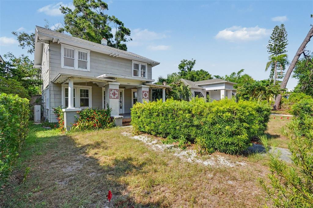 A two-story gray house with a front porch stands behind a large green hedge — 5441 1ST AVENUE N, ST PETERSBURG, FL