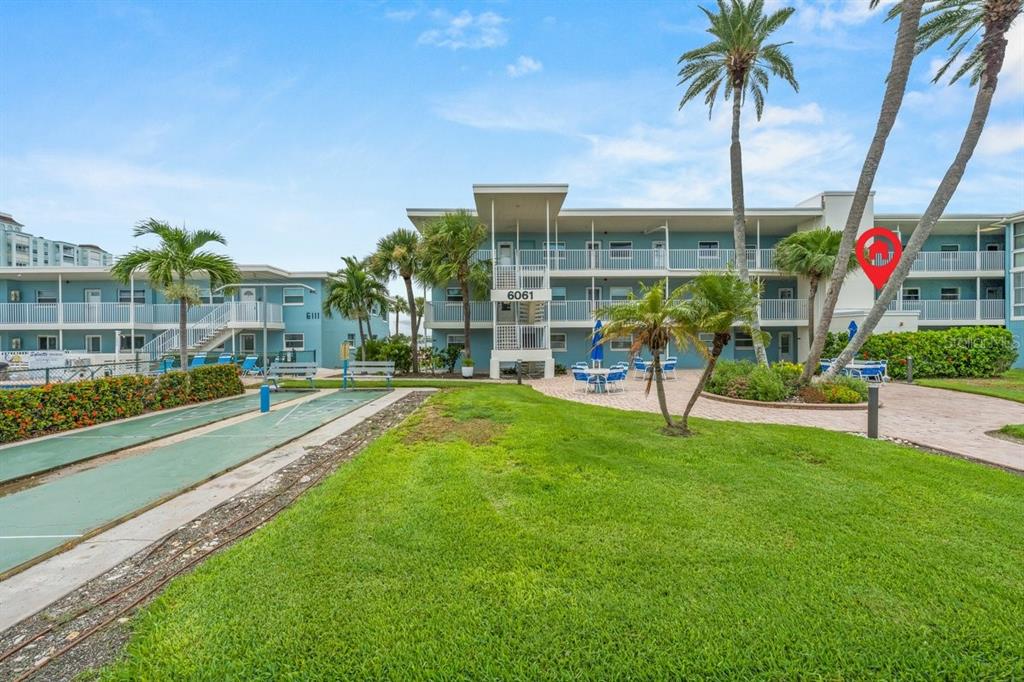 A multi-story apartment building with a shuffleboard court and palm trees in the foreground — 6061 2ND STREET E UNIT 45, ST PETERSBURG, FL