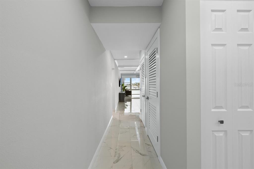 A hallway with light-colored tile flooring leads toward a bright living area with water views — 6061 2ND STREET E UNIT 45, ST PETERSBURG, FL