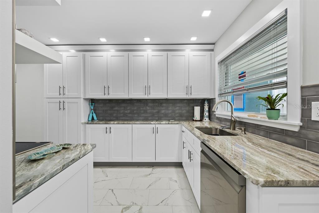 A kitchen with white cabinets, gray subway tile backsplash, and marble-patterned countertops and flooring — 6061 2ND STREET E UNIT 45, ST PETERSBURG, FL