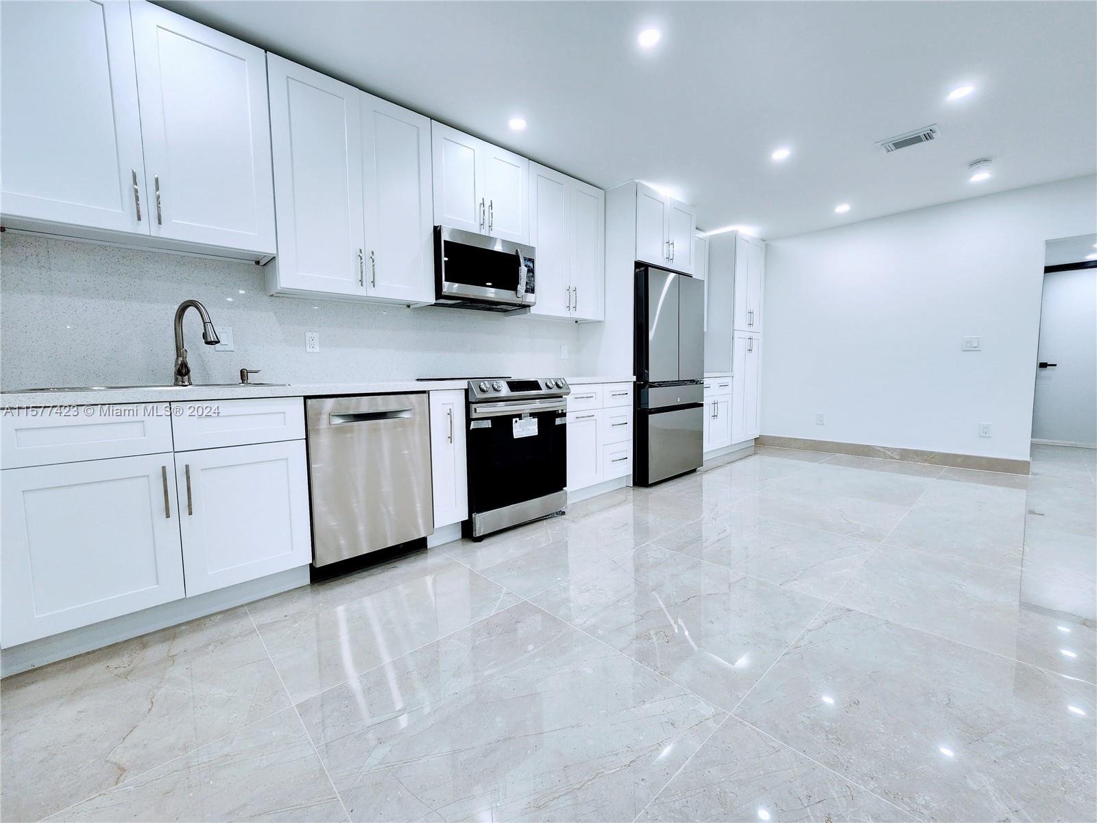 A modern kitchen features white cabinetry, stainless steel appliances, and light-colored tile flooring — 11930 NE 19th Dr # 3, North Miami FL 33181, NORTH MIAMI, FL