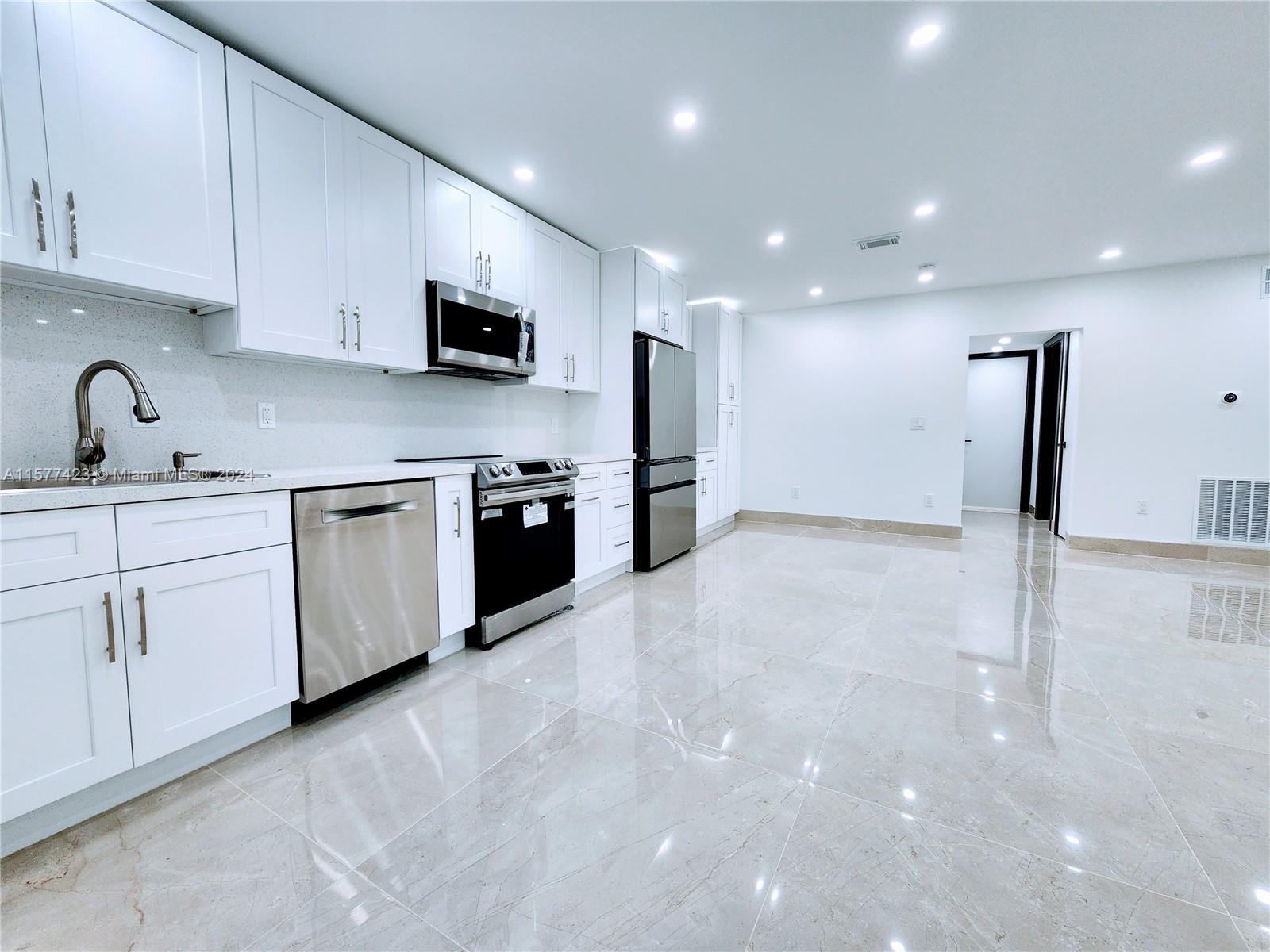 A modern kitchen features white cabinets, stainless steel appliances, and light-colored tile flooring — 11930 NE 19th Dr # 3, North Miami FL 33181, NORTH MIAMI, FL