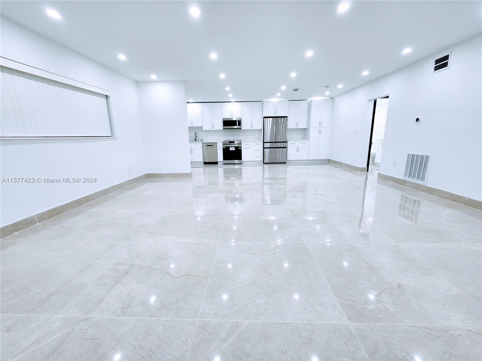 A bright, open-concept kitchen features white cabinetry, stainless steel appliances, and polished tile flooring — 11930 NE 19th Dr # 3, North Miami FL 33181, NORTH MIAMI, FL