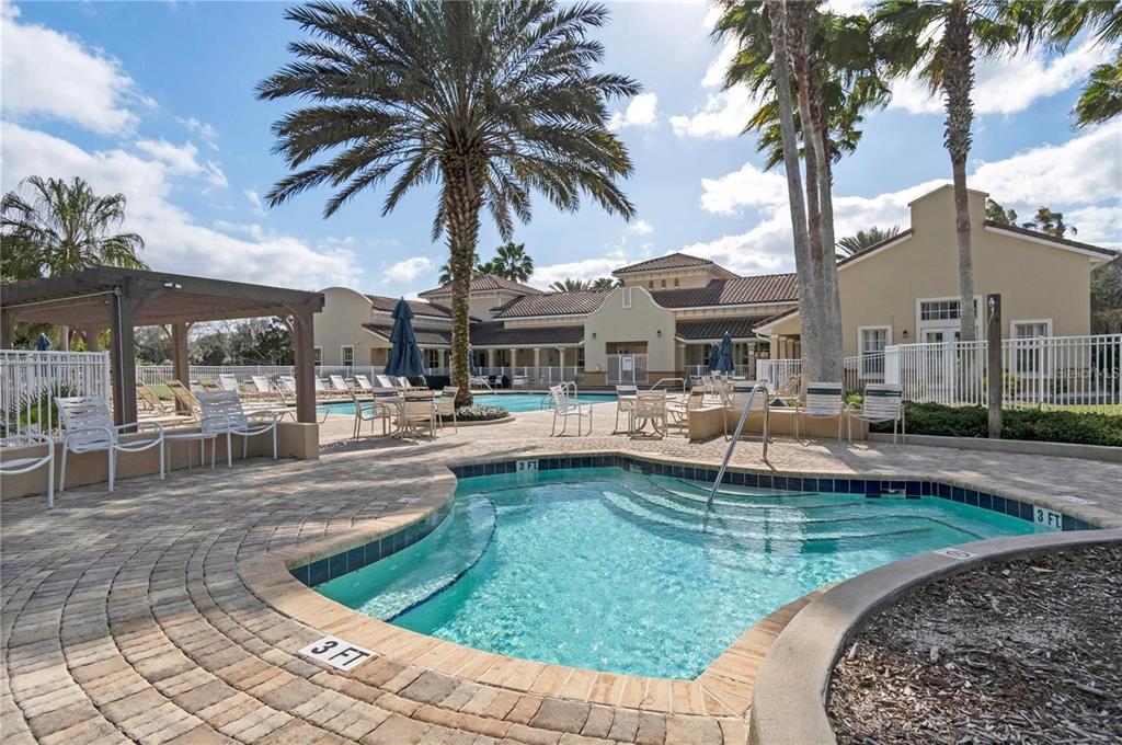 A swimming pool and hot tub are surrounded by a patio, lounge chairs, and palm trees — 35 RIVERVIEW BEND S UNIT 1841, PALM COAST, FL