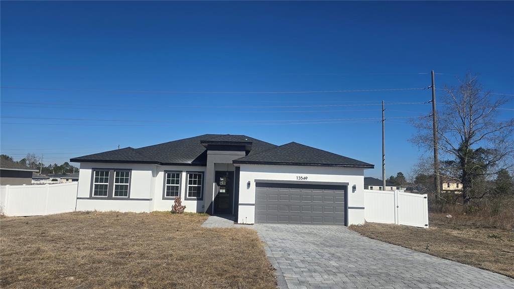 A single-story house with a white exterior, dark roof, and a paved driveway — 13549 SW 47TH CIRCLE, OCALA, FL