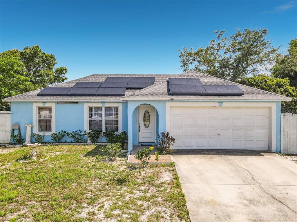 A light blue single-story house with a white garage door and roof-mounted solar panels — 1473 PURITAN STREET, DELTONA, FL