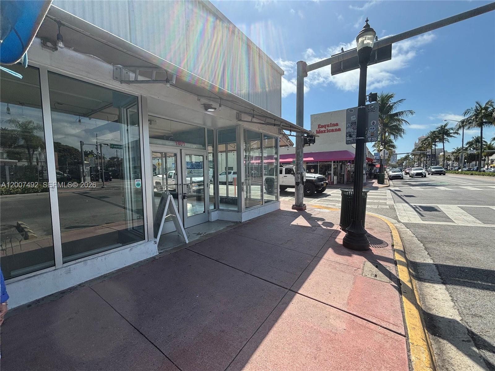 A street-level view of a commercial storefront with large glass windows on a corner sidewalk — 1407 Washington Ave # 1401, Miami Beach FL 33139, MIAMI BEACH, FL