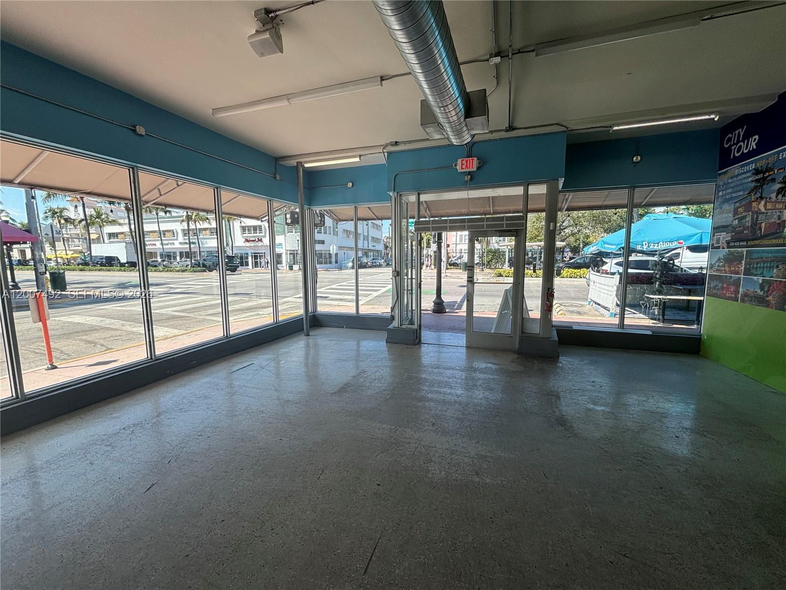 An empty commercial space features large glass windows, concrete floors, and an exposed ceiling duct — 1407 Washington Ave # 1401, Miami Beach FL 33139, MIAMI BEACH, FL