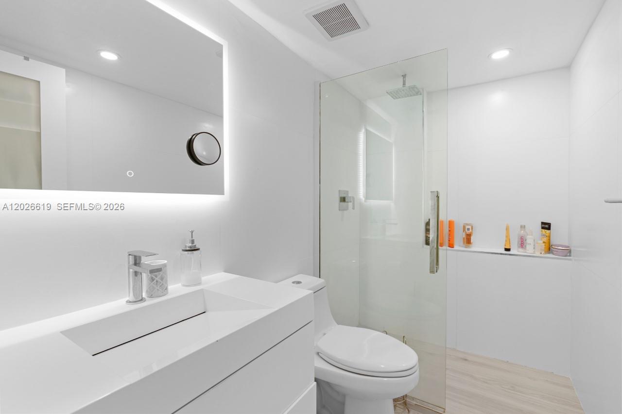 A modern bathroom features a white vanity, a backlit mirror, and a glass-enclosed walk-in shower — 1500 Bay Rd # 1268S, Miami Beach FL 33139, MIAMI BEACH, FL