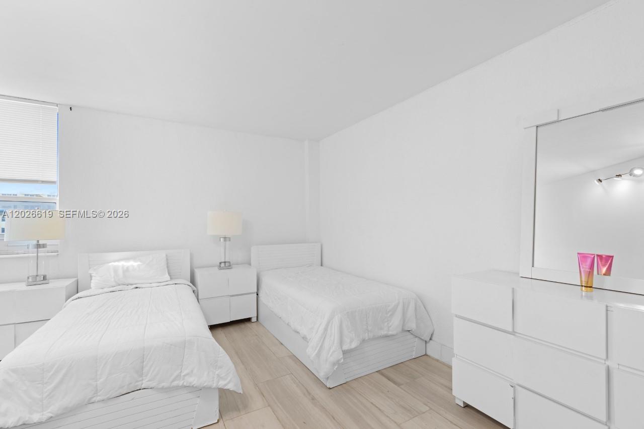 A bedroom features two white twin beds, a nightstand, and a white dresser with a mirror — 1500 Bay Rd # 1268S, Miami Beach FL 33139, MIAMI BEACH, FL