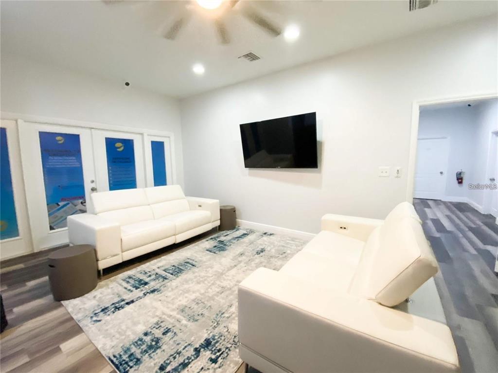A living room features two white sofas, a patterned area rug, and a wall-mounted television — 103 BROADWAY UNIT 206, KISSIMMEE, FL