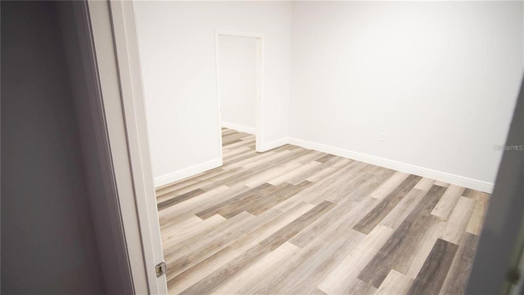 An empty room features light gray walls and wood-look vinyl plank flooring — 103 BROADWAY UNIT 206, KISSIMMEE, FL