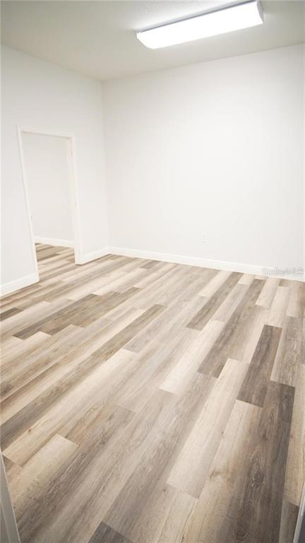 An empty room features light-colored walls, a rectangular ceiling light, and wood-look vinyl flooring — 103 BROADWAY UNIT 206, KISSIMMEE, FL