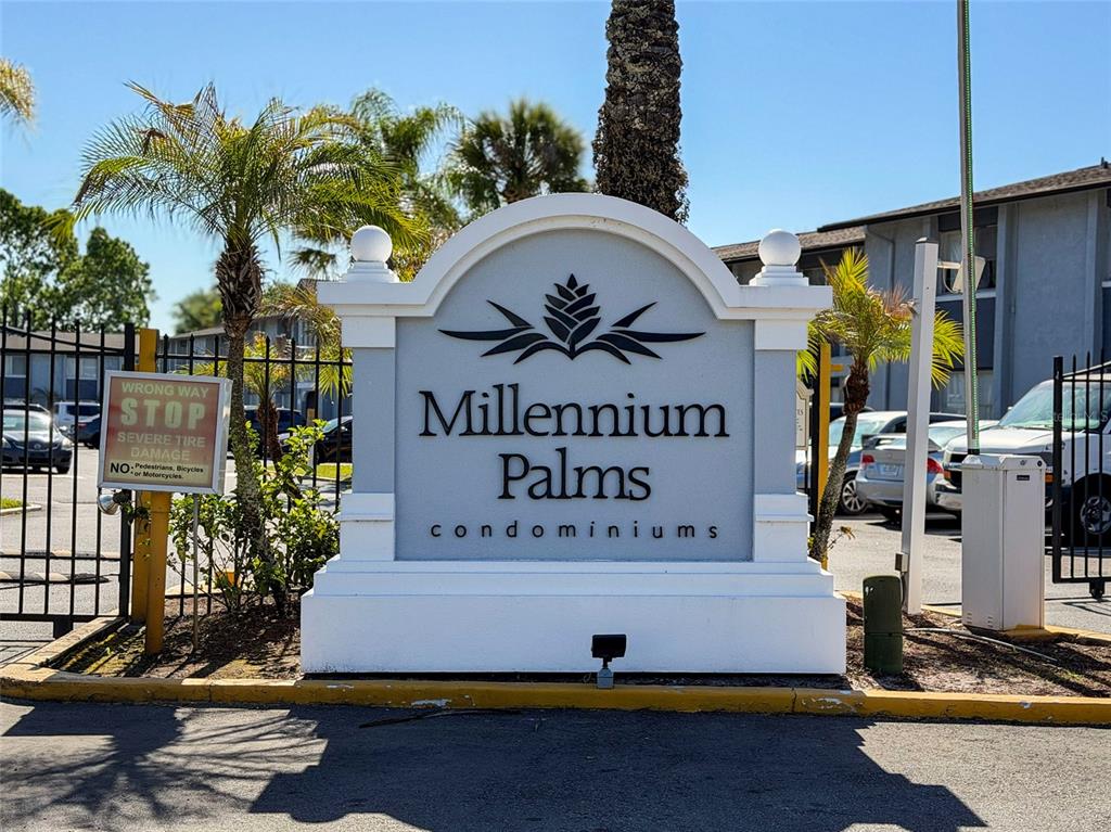 A sign for Millennium Palms condominiums stands at the entrance to a gated parking lot — 4789 S TEXAS AVENUE UNIT 4789D, ORLANDO, FL