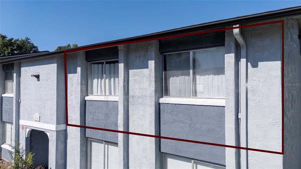 The exterior of a two-story apartment building features gray stucco walls and sliding windows — 4789 S TEXAS AVENUE UNIT 4789D, ORLANDO, FL