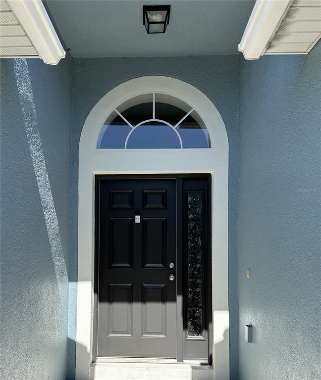 A front entryway features a black door with a sidelight and an arched transom window — 5539 SYCAMORE CANYON DRIVE, KISSIMMEE, FL