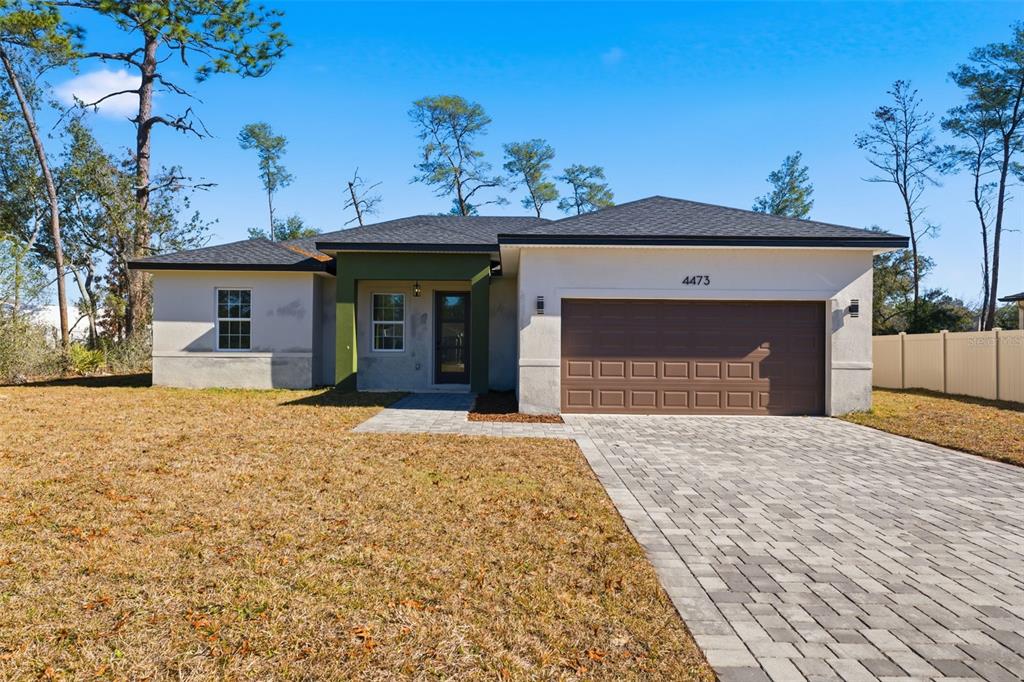 A single-story house with a paved driveway, a brown garage door, and green entryway accents — 4473 SW 168TH LANE, OCALA, FL