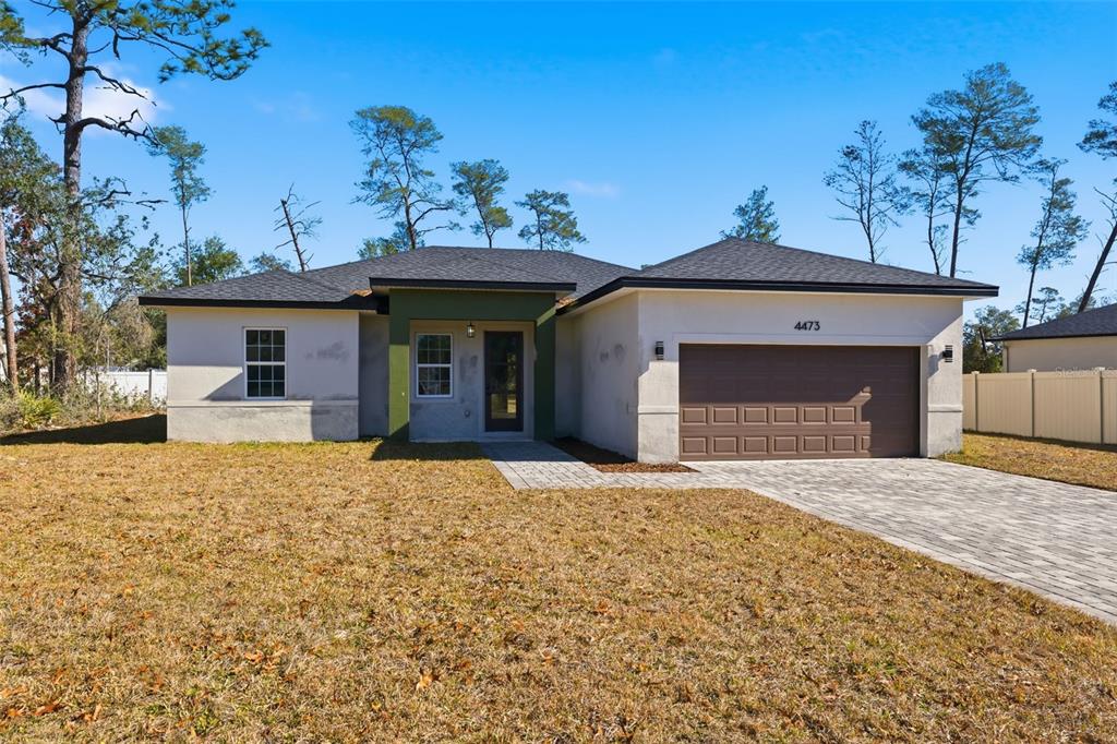 A single-story house with a white stucco exterior, dark roof, and a paved driveway — 4473 SW 168TH LANE, OCALA, FL