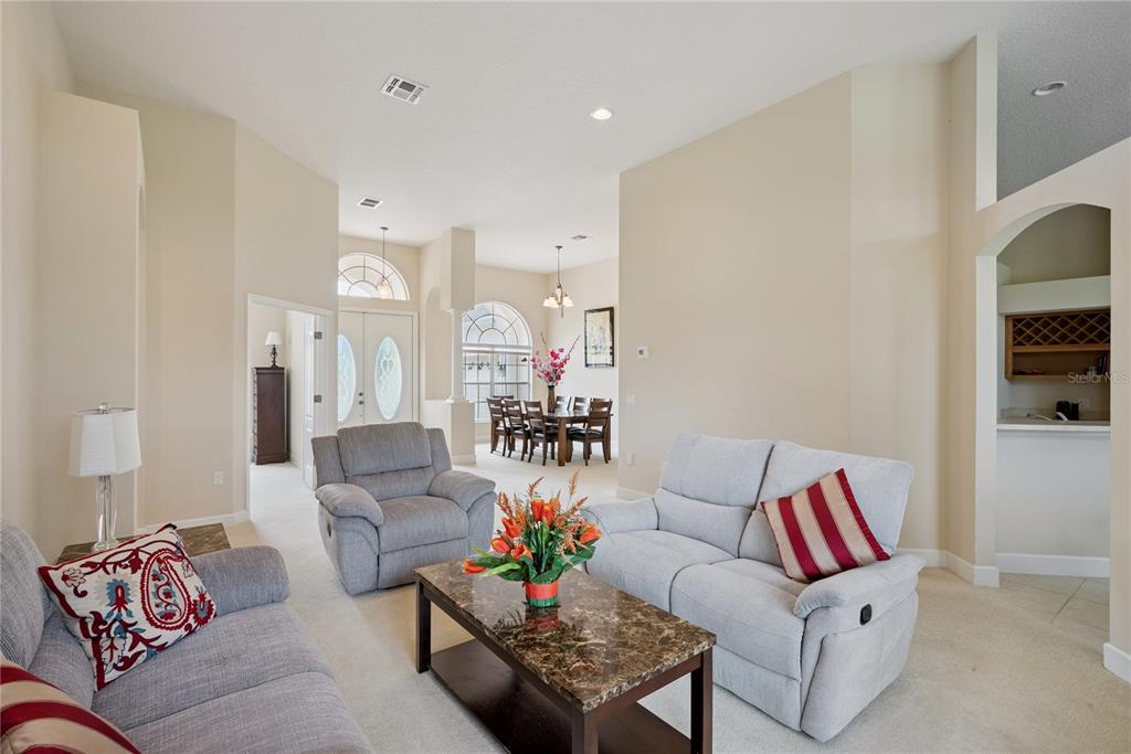 A living room with light gray furniture and a coffee table opens to a dining area — 3700 DUNOON COURT, APOPKA, FL