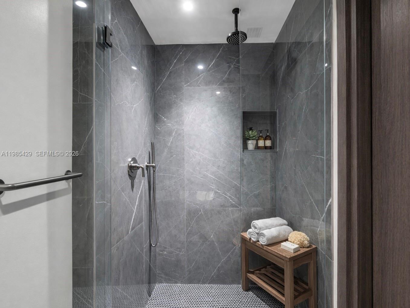 A walk-in shower features dark gray marble-look tiles, a built-in niche, and a wooden bench — 20 NE 11 ST # 2306B, Miami FL 33132, MIAMI, FL