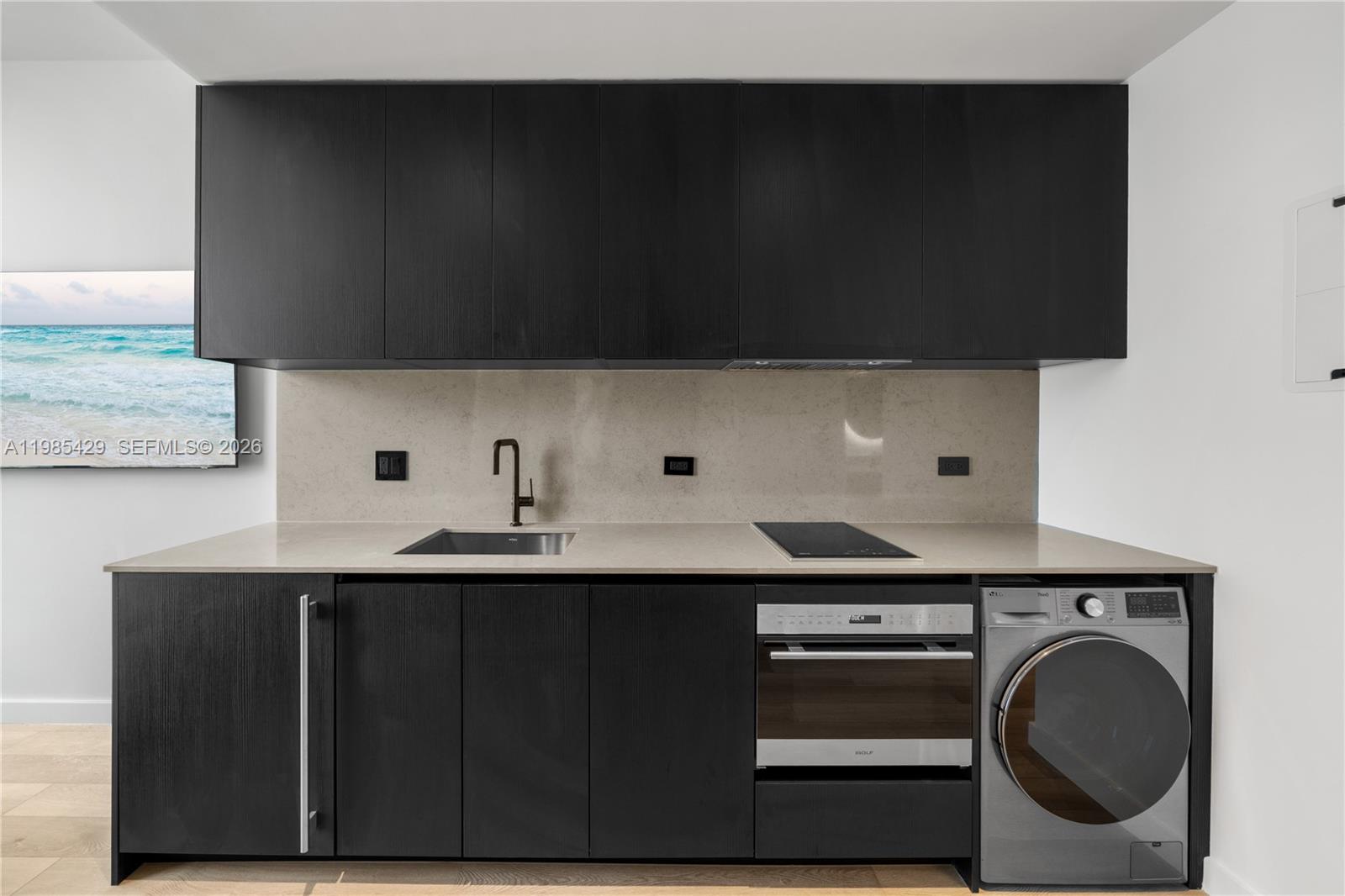 A modern kitchenette features black cabinets, a stainless steel oven, and an integrated washing machine — 20 NE 11 ST # 2306B, Miami FL 33132, MIAMI, FL
