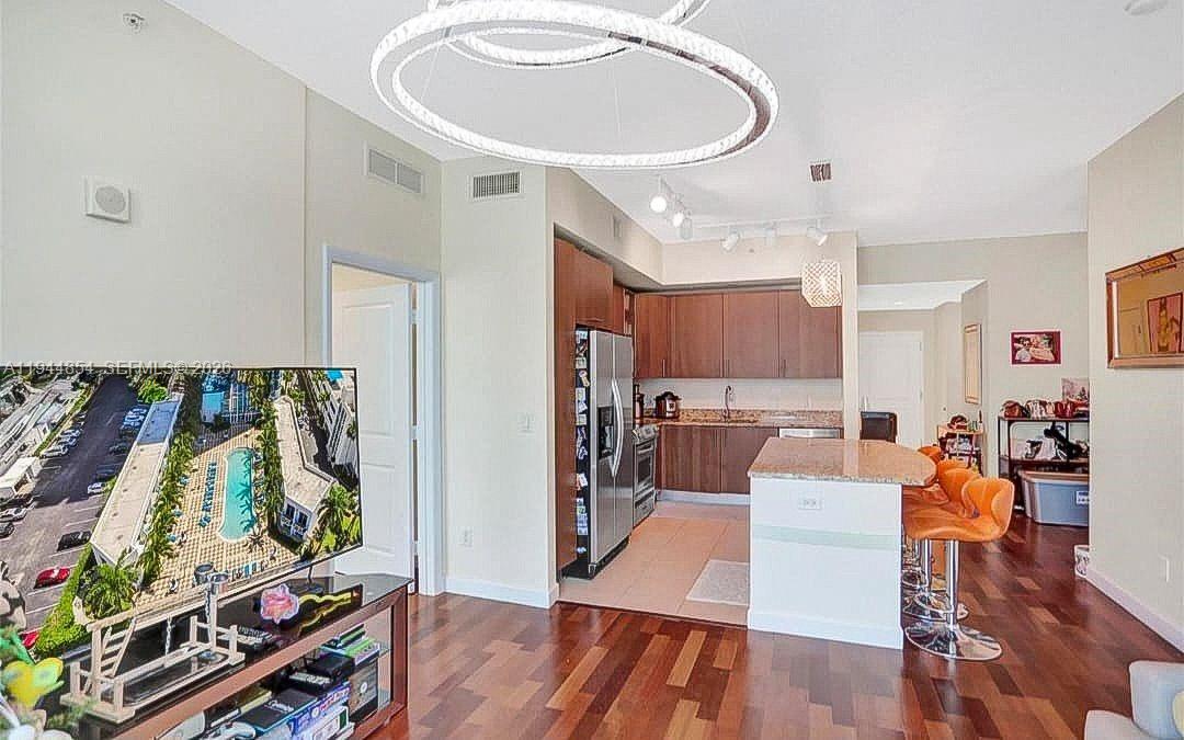 An open-concept kitchen and living area features wood flooring, a central island, and modern lighting — 1945 S Ocean Dr # 1405, Hallandale Beach FL 33009, HALLANDALE BEACH, FL