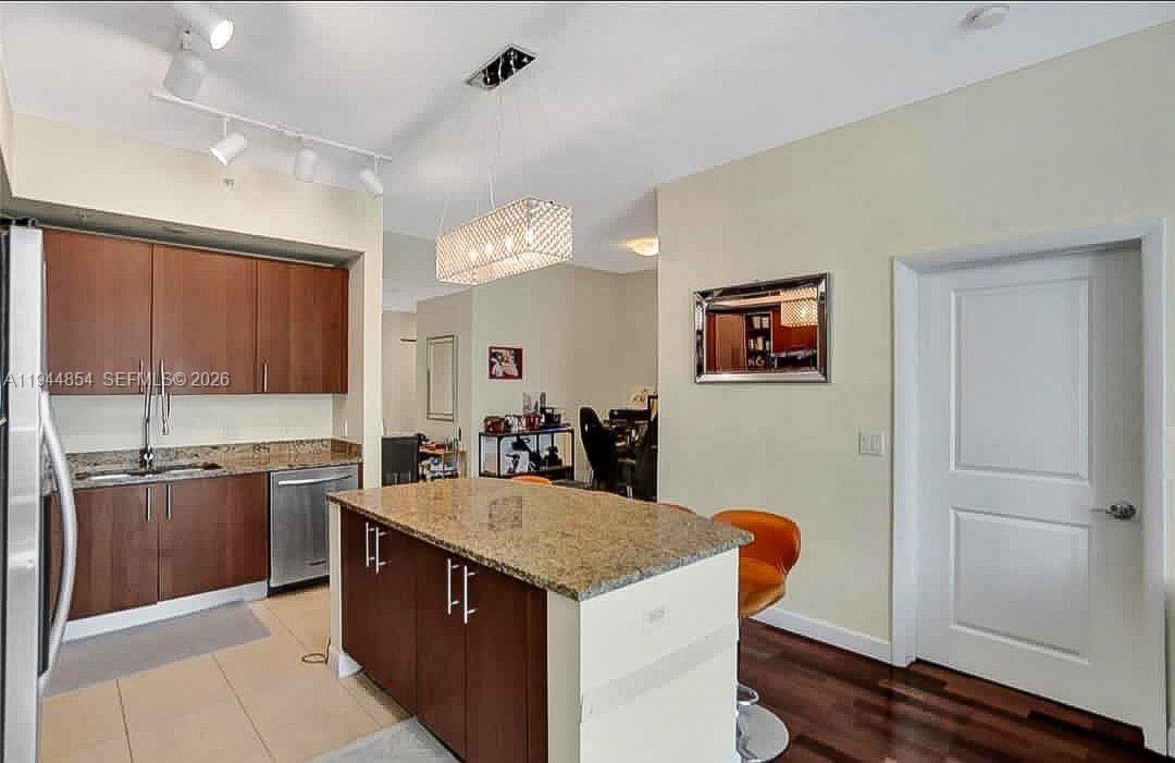 A kitchen features wood cabinets, granite countertops, a center island, and a pendant light fixture — 1945 S Ocean Dr # 1405, Hallandale Beach FL 33009, HALLANDALE BEACH, FL