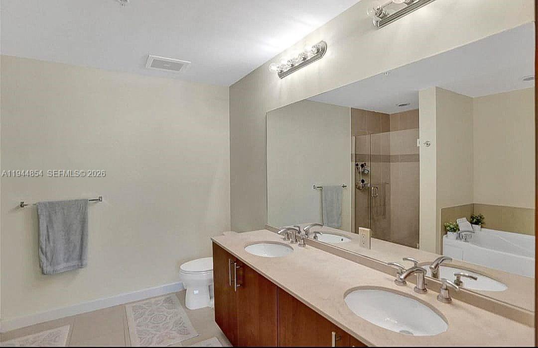 A bathroom features a double vanity with a beige countertop, a toilet, and a shower — 1945 S Ocean Dr # 1405, Hallandale Beach FL 33009, HALLANDALE BEACH, FL