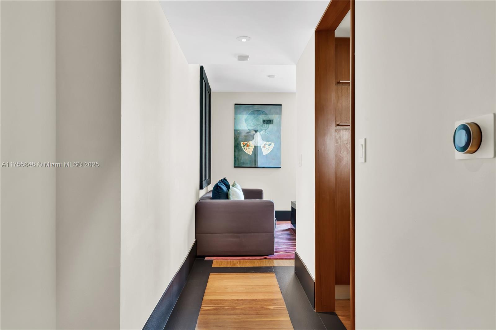 A hallway with dark flooring leads to a small seating area with a sofa — 101 20, Miami Beach FL 33139, MIAMI BEACH, FL