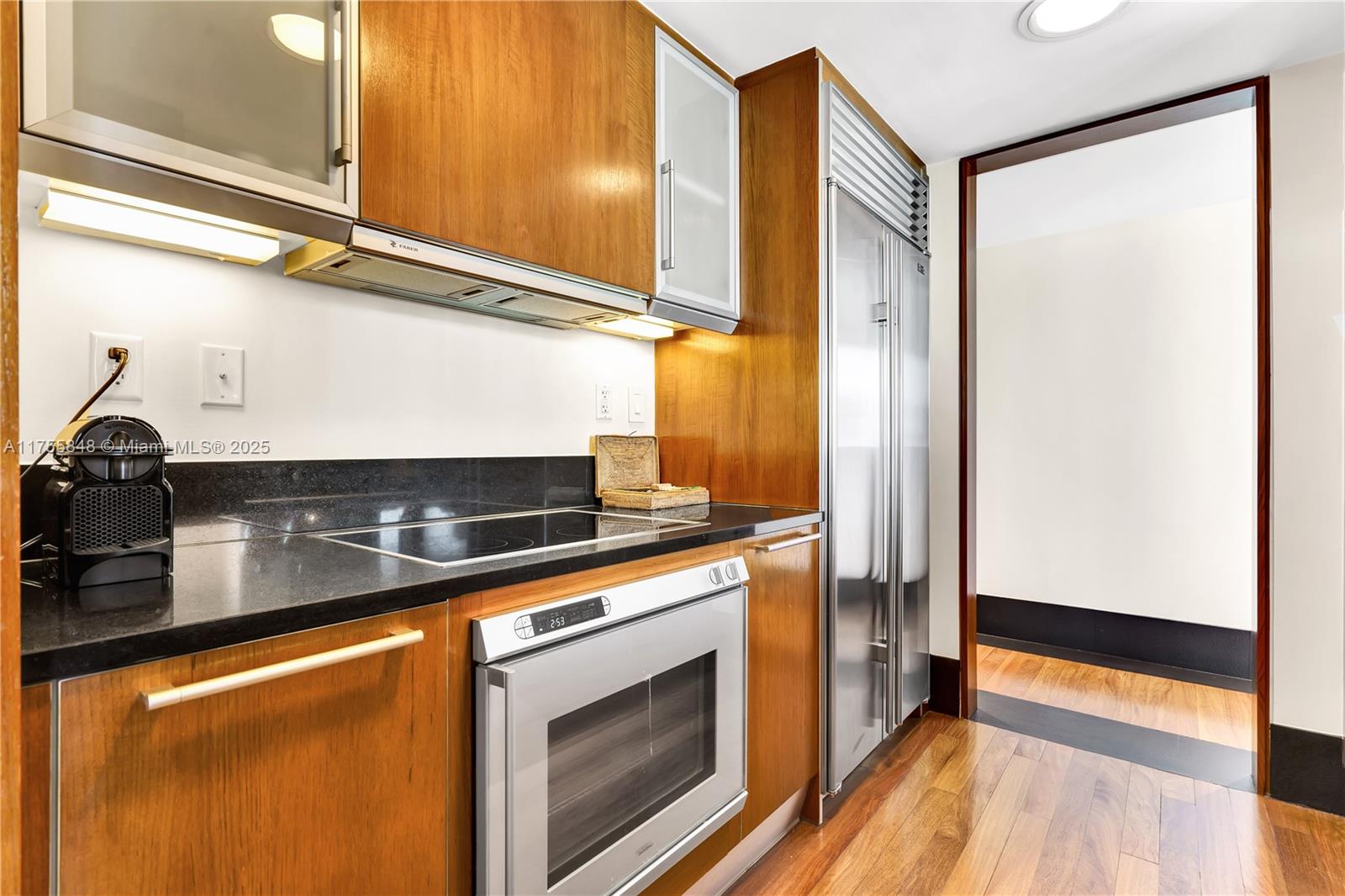 A kitchen features wood cabinetry, stainless steel appliances, and black countertops — 101 20, Miami Beach FL 33139, MIAMI BEACH, FL