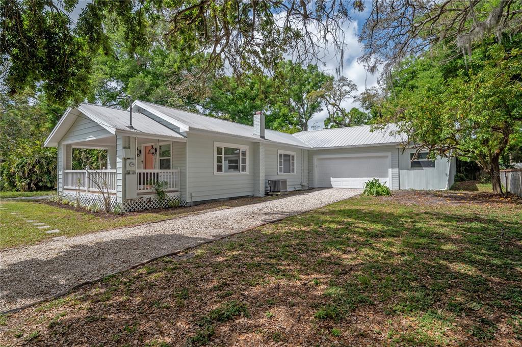 A single-story house with light siding, a metal roof, a front porch, and a gravel driveway — 4206 N DOWNING AVENUE, TAMPA, FL