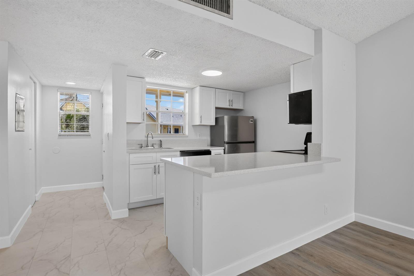 A kitchen with white cabinets, stainless steel appliances, and a breakfast bar peninsula — 6323 La Costa Drive # M, Boca Raton FL 33433, BOCA RATON, FL