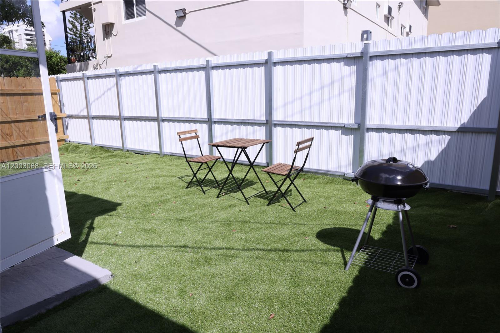 A small backyard features artificial turf, a metal fence, a bistro set, and a grill — 1109 SW 37th Ave # 1115, Miami FL 33135, MIAMI, FL