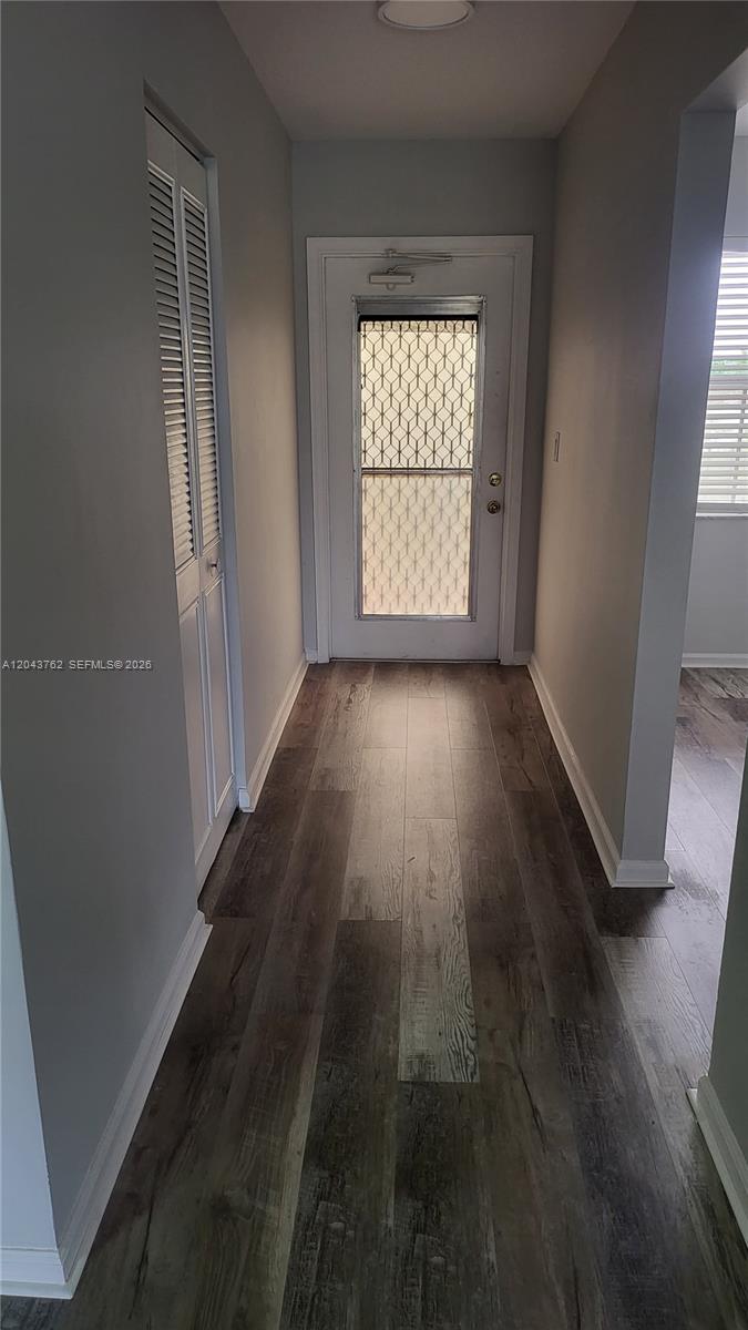 A hallway features wood-look flooring, light gray walls, and a white door with a screen — 7220 Lake Cir Dr # 406, Margate FL 33063, MARGATE, FL