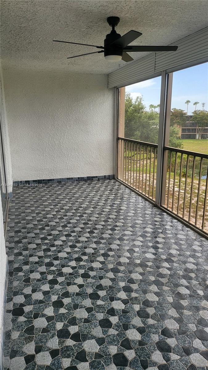 A covered balcony features a patterned stone-look floor, a ceiling fan, and screened-in railings — 7220 Lake Cir Dr # 406, Margate FL 33063, MARGATE, FL