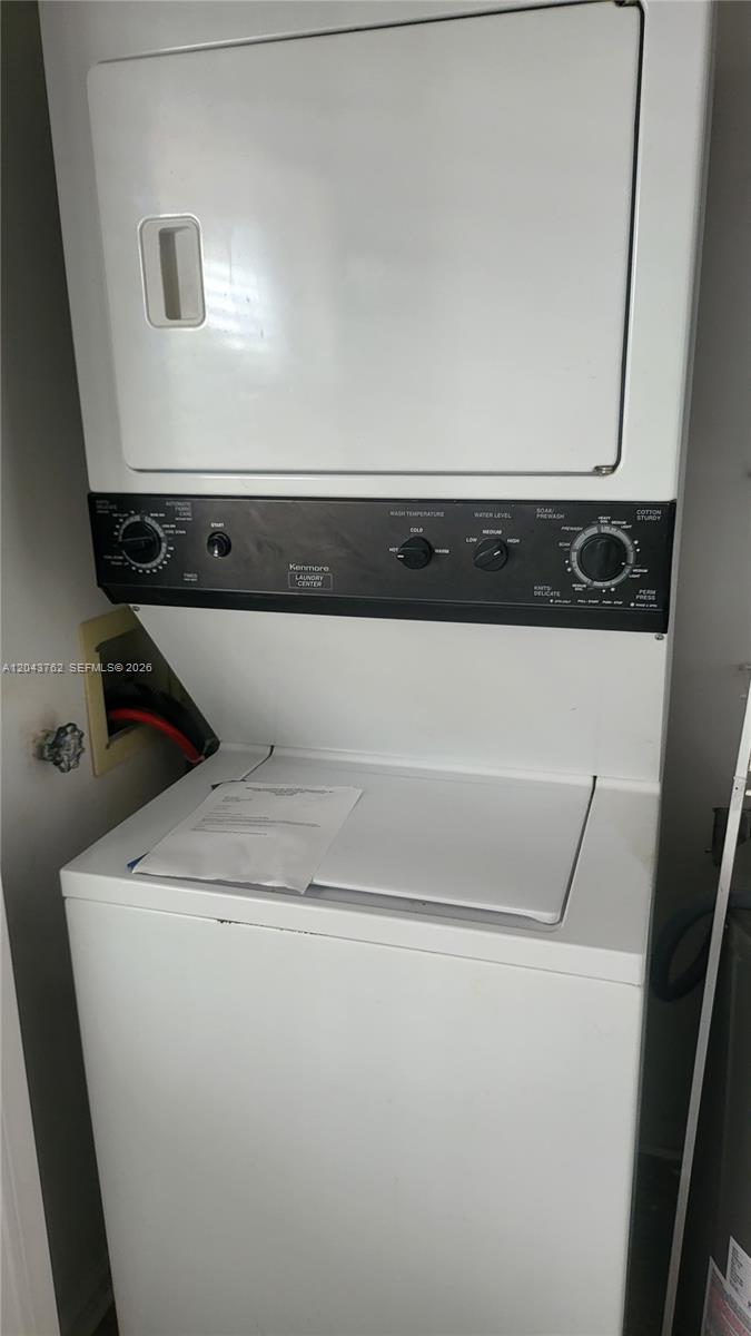 A white Kenmore stacked washer and dryer unit sits in a small laundry closet — 7220 Lake Cir Dr # 406, Margate FL 33063, MARGATE, FL