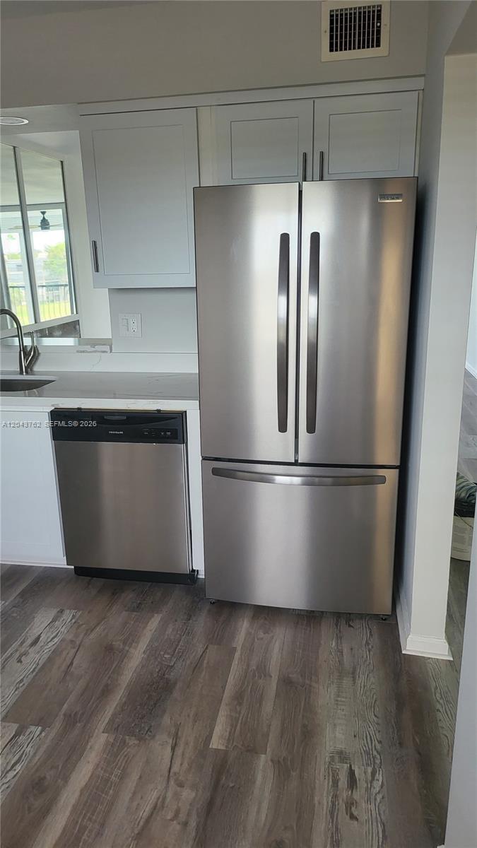 A kitchen features stainless steel appliances, light gray cabinets, and wood-look flooring — 7220 Lake Cir Dr # 406, Margate FL 33063, MARGATE, FL