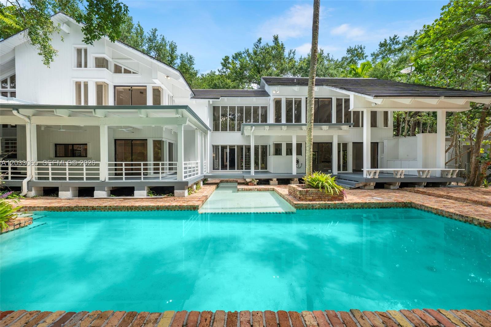 A two-story white house with a large swimming pool and a brick patio — 5600 Oakwood Ln, Coral Gables FL 33156, CORAL GABLES, FL