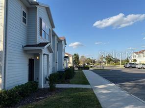 A side view of a light blue multi-story residential building with a sidewalk and parking lot — 8962 SILVER PLACE, KISSIMMEE, FL